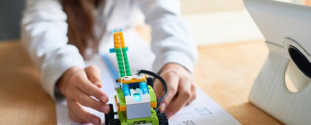 Image of child playing with a Lego robot, next to an i-pad.