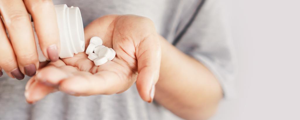 closeup woman hand holding medicine bottle taking overdose pills